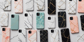 A collection of 10 marble phone cases in various colors and patterns, arranged neatly on a white marble surface.